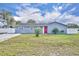 Charming single-story home featuring a red front door, well-manicured lawn, and white fence at 397 Oslo Dr, Deltona, FL 32725