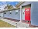 Close-up of a red front door with white trim, flanked by a well-manicured lawn and walkway at 397 Oslo Dr, Deltona, FL 32725