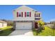 Two-story home featuring stone accents, a two-car garage, red shutters, and a bright red door at 4152 Sagefield Dr, Harmony, FL 34773