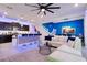 Open-concept living space with a sleek white sectional, kitchen bar seating, and a dining area under a modern chandelier at 4210 Lana Ave, Davenport, FL 33897