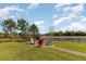 Backyard seating area next to a serene pond surrounded by lush landscaping and blue skies at 4672 Marina Row Dr, Orlando, FL 32820
