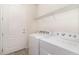 Bright laundry room featuring a modern washer and dryer, wire shelf, and a door at 4672 Marina Row Dr, Orlando, FL 32820