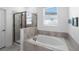 Bright bathroom featuring a soaking tub with tile surround and a glass-enclosed shower at 5052 Blanchard Ct, St Cloud, FL 34772