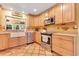 Spacious kitchen featuring tile floors, stainless steel appliances, and natural wood cabinetry at 5263 Jade Cir, Belle Isle, FL 32812