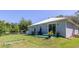 View of the fenced-in backyard with a hot tub, artificial turf, and sliding glass door access at 5694 Aragon Ave, De Leon Springs, FL 32130