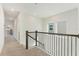 Upstairs hallway with neutral carpet, dark banister and natural light from the windows at 6525 Rover Way, St Cloud, FL 34771