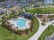 Aerial view of community pool surrounded by lounge chairs, a playground, and lush green space with a neighborhood in the background at 6525 Rover Way, St Cloud, FL 34771