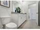 Bathroom showcasing a granite countertop vanity and toilet, leading into an open hallway at 866 Pebble Crest Ln, Eagle Lake, FL 33839