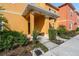 Inviting townhome entrance featuring a well-manicured landscape, covered porch, and cheerful, warm exterior color at 8963 Majesty Palm Rd, Kissimmee, FL 34747