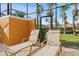 Two lounge chairs and view to exterior in screened lanai with tall palms and well maintained lawn at 8963 Majesty Palm Rd, Kissimmee, FL 34747