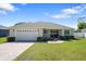 Charming single-story home with a paved driveway, two-car garage, and well-maintained lawn at 130 Islabella Way, Groveland, FL 34736