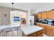 Well-lit kitchen seamlessly connects to bonus room, featuring an island, stainless steel refrigerator, and neutral tones at 14230 Sunriver Ave, Orlando, FL 32828