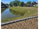 Captured view of a serene pond, framed by lush greenery and secured by a chain-link fence at 1510 Massa St, Kissimmee, FL 34744
