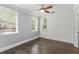 This neutral bedroom has hardwood floors, white trim, ceiling fan, and three windows at 1563 Common Way Rd, Orlando, FL 32814