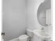 Cozy half bathroom offering a pedestal sink, toilet, and circular mirror at 1563 Common Way Rd, Orlando, FL 32814