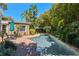 Backyard view showcasing a sparkling in-ground pool with brick patio, mature tropical landscaping, and lounge seating at 1621 Chippewa Trl, Maitland, FL 32751