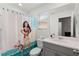 Bright bathroom features a Moana-themed shower curtain, white cabinets and a window for natural light at 1799 Tropical Palms Cir, Kissimmee, FL 34747