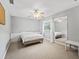 Neutral bedroom with a ceiling fan, window, large mirror, and bed with a white duvet at 208 Hideaway Ct, Minneola, FL 34715