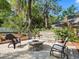 A stone fire pit surrounded by three chairs on a brick patio and greenery creates a cozy backyard space at 208 Hideaway Ct, Minneola, FL 34715