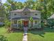 Charming two-story home with a stone accent tower and covered front porch surrounded by lush, mature trees at 208 Hideaway Ct, Minneola, FL 34715