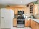 Kitchen with wood cabinets, stainless steel appliances, granite counters and a white refrigerator at 208 Hideaway Ct, Minneola, FL 34715