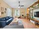 Bright living room featuring a ceiling fan, hardwood floors, and a large blue couch at 208 Hideaway Ct, Minneola, FL 34715