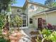 This home features a screened in porch, red entry door, and an abundance of surrounding plants at 208 Hideaway Ct, Minneola, FL 34715