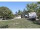 A spacious backyard with a shed, lush trees, green grass, sandy patches, and an RV parked to the right at 211 Agua Vista St, Debary, FL 32713