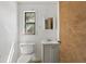 A clean half bathroom featuring a toilet, sink with vanity, mirror, and a window for natural light at 211 Agua Vista St, Debary, FL 32713