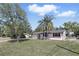 Charming single-story home featuring a manicured lawn, freshly painted white exterior, and beautiful palm trees at 211 Agua Vista St, Debary, FL 32713