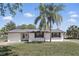 Charming single-story home featuring a manicured lawn, freshly painted white exterior, and beautiful palm trees at 211 Agua Vista St, Debary, FL 32713