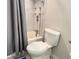 A bathroom with a white toilet, shower and gray curtain and marble tiled shower walls at 3024 Natoma Way, Orlando, FL 32825