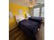 Bedroom with yellow accent wall featuring two twin beds with wood-look laminate flooring at 4573 Ada Ln, Kissimmee, FL 34746