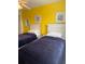 Bedroom with yellow accent wall featuring two twin beds with wood-look laminate flooring at 4573 Ada Ln, Kissimmee, FL 34746