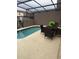 Cozy backyard pool featuring a patio table, chairs, and screened enclosure for private outdoor living at 4573 Ada Ln, Kissimmee, FL 34746