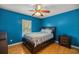 Bedroom with blue walls, a ceiling fan, a wood-framed bed, and hardwood floors at 8499 Se 155Th, Summerfield, FL 34491