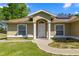 Home featuring a covered front entrance with stately white columns and a well manicured lawn at 8499 Se 155Th, Summerfield, FL 34491