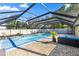 Beautiful screened pool area with a lounging area and lush greenery in the background at 8499 Se 155Th, Summerfield, FL 34491