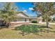 Side view of a cozy home featuring a brick foundation, lush lawn, and mature trees at 8703 Grandee Dr, Orlando, FL 32829