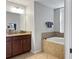 Well-lit bathroom featuring a soaking tub, dark wood vanity, and tiled floors at 8908 Azalea Sands Ln, Davenport, FL 33896