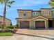 Two-story exterior showcasing a brick driveway, attached garages, and green paint accented by stonework details at 8908 Azalea Sands Ln, Davenport, FL 33896