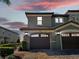 Two-story exterior at dusk showcasing attached garages and green paint accented by stone at 8908 Azalea Sands Ln, Davenport, FL 33896