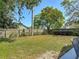 Large, grassy backyard enclosed by a wood fence and mature landscaping under a blue sky at 101 Sandpebble Pl, Sanford, FL 32771