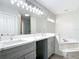 Spacious bathroom featuring double vanities, a large mirror, and soaking tub with marble surround at 101 Sandpebble Pl, Sanford, FL 32771