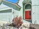 Close-up of a home's entrance with a red front door, lovely landscaping, and a two-car garage at 101 Sandpebble Pl, Sanford, FL 32771