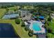 An aerial view of the community pool and clubhouse, with adjacent tennis courts and lush landscaping at 12613 Maribou Cir, Orlando, FL 32828
