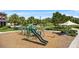 Community playground featuring slides, climbing bars, and swings, surrounded by wood chips and landscaping at 17668 Passionflower Cir, Clermont, FL 34714