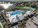 Stunning aerial view of community pool, tennis courts, and clubhouse, all surrounded by lush greenery and a serene lake at 1807 Good Neighbor Loop, Kissimmee, FL 34744