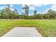 Expansive backyard with a green lawn, bordered by lush trees, and a concrete pad ready for outdoor activities at 21145 Sw Great Lakes Blvd, Dunnellon, FL 34431