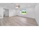 Bright living room with light wood flooring, ceiling fan, and large window overlooking green outdoors at 21145 Sw Great Lakes Blvd, Dunnellon, FL 34431